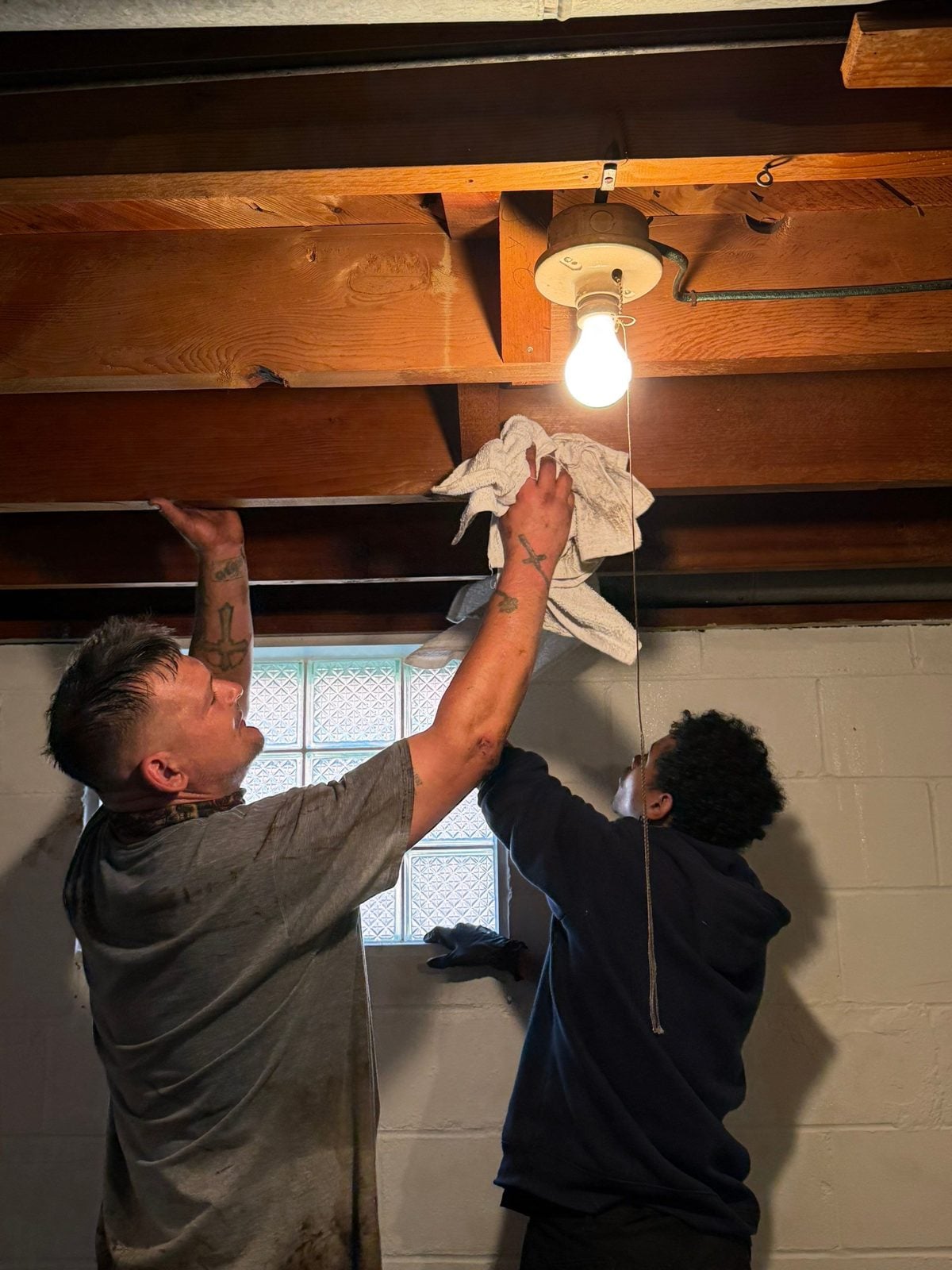 Steel City Property Restoration crew cleaning basement ceiling joists during mold remediation in Greensburg, PA
